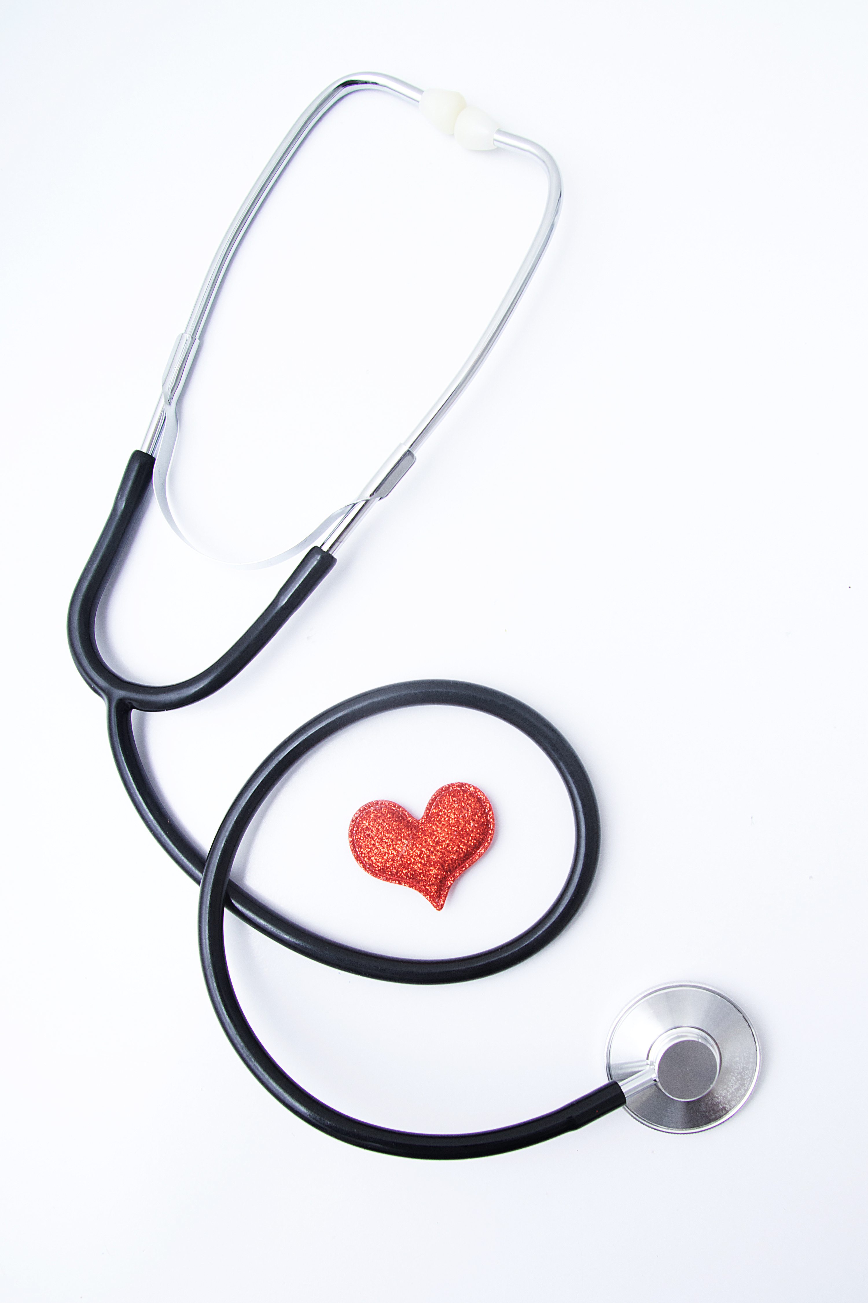 Red heart with medical stethoscope. Insurance health or heart treatment, mental health concept. Flat lay vertical format.